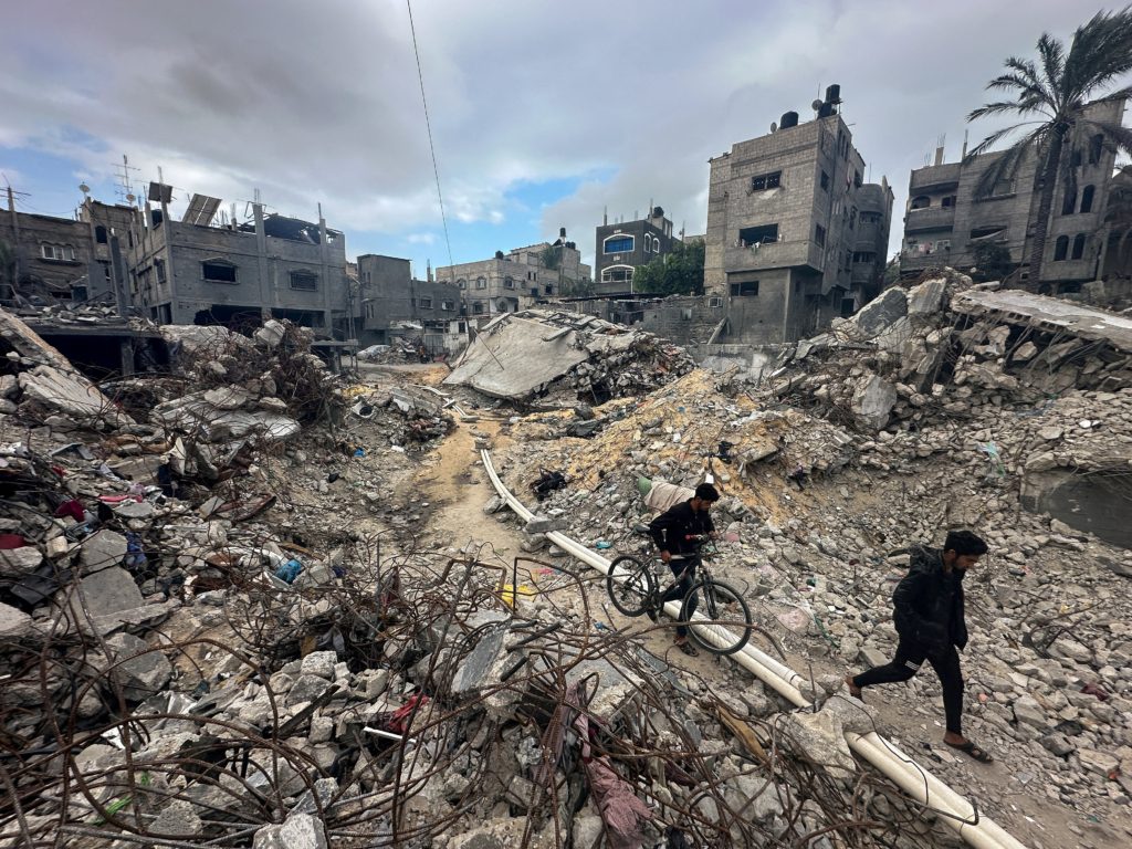 فلسطينيون يسيرون بين الأنقاض، وهم يتفقدون المنازل التي دمرتها الضربات الإسرائيلية في مخيم خان يونس للاجئين في جنوب قطاع غزة/رويترز
